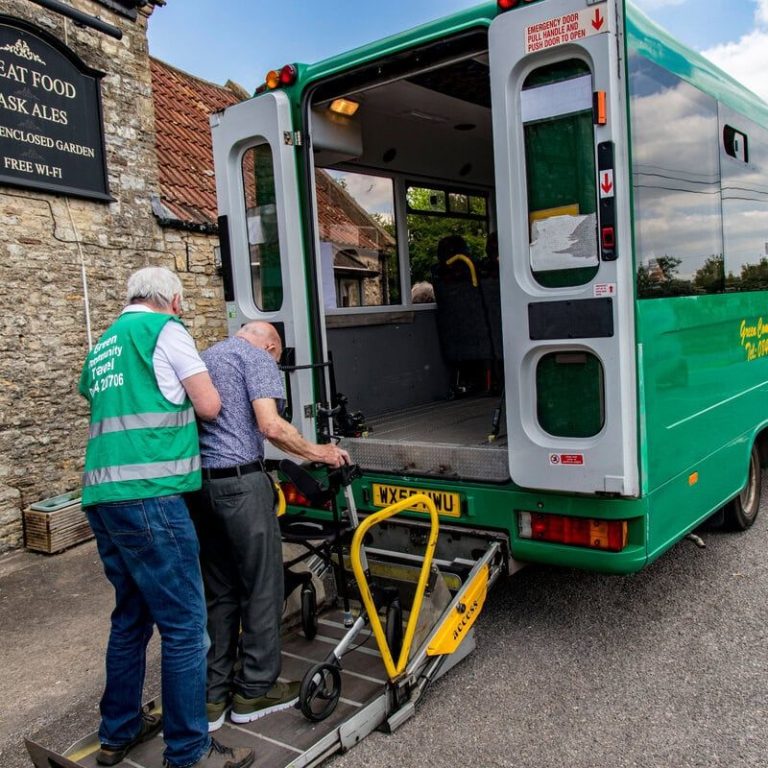 A Green Community Transport volunteer driver helps a man into the minibus.